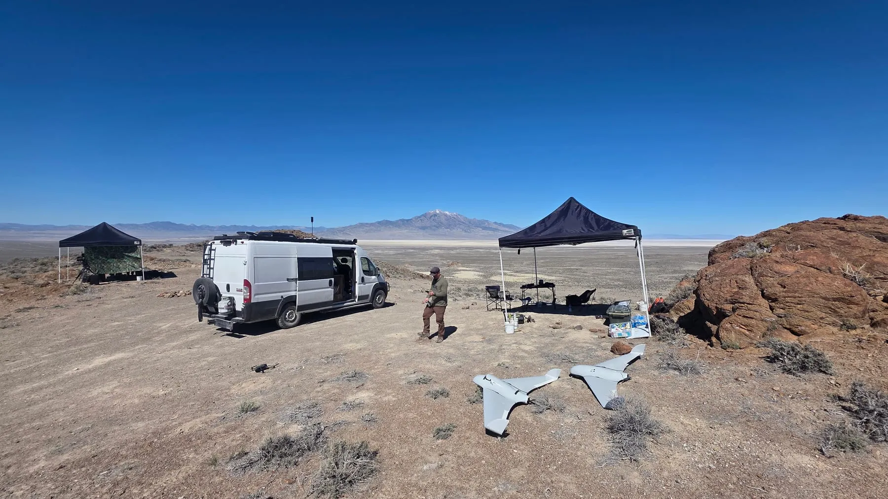 A vehicle, canopy, and aircraft set up for operations in open desert terrain.